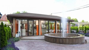 A modern building with a glass facade, a circular water feature, and a brick patio.