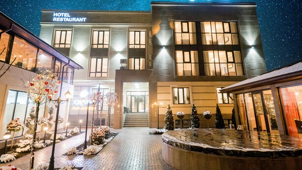 Ein Hotel mit moderner Fassade, einem sichtbaren Eingang und einem Schild, das auf ein hoteleigenes Restaurant hinweist.
