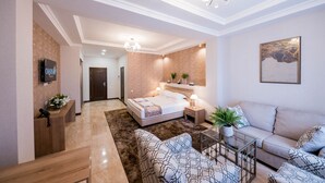 Ein modernes Hotelzimmer mit einem großen Bett, einem Sofa, einem Couchtisch und einem Fernseher.
