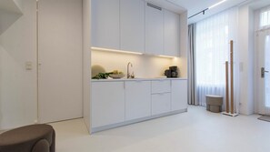 A modern kitchen with white cabinetry, a built-in oven, and a coffee maker on the counter.