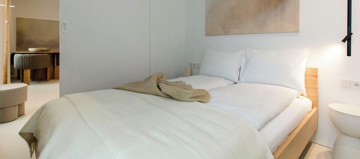 Un dormitorio moderno con una cama grande, mesitas de noche y una lámpara fijada a la pared.
