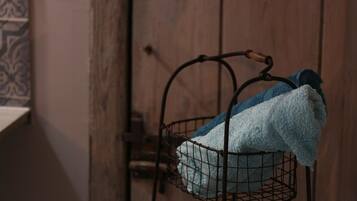 Een metalen mand met een blauwe handdoek, hangend aan een wandrek in een kamer met houten lambrisering.