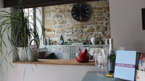 A kitchen with a stone wall, a clock, and various kitchen items.