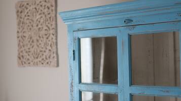 Una puerta azul con paneles de vidrio, una obra de arte en relieve en la pared y una pared lisa.