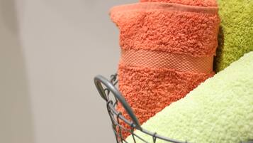A metal basket containing three towels in different colors.