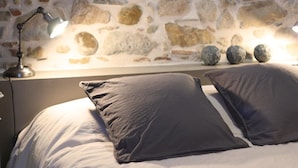 A bed with grey pillows and a lamp on a nightstand.