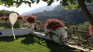 A garden with a heart-shaped balloon, potted plants, and a view of a mountainous landscape.