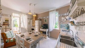 A kitchen with a dining table set for four, a refrigerator, and a sink.