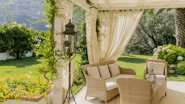 A covered outdoor seating area with wicker furniture and a lantern.