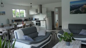 A modern living room with a grey sofa, a coffee table, and a dining area with a table and chairs. - Beautiful new villa, quiet, near forest Biscarrosse / 6p (Biscarrosse)