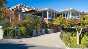 Una moderna casa a due piani con un portico coperto, un garage e un vialetto.