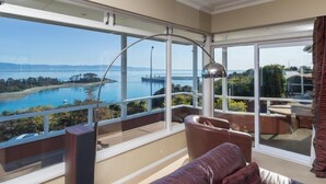 Un balcone con vista su un corso d'acqua e un ponte, arredato con un divano in pelle e un tavolo.