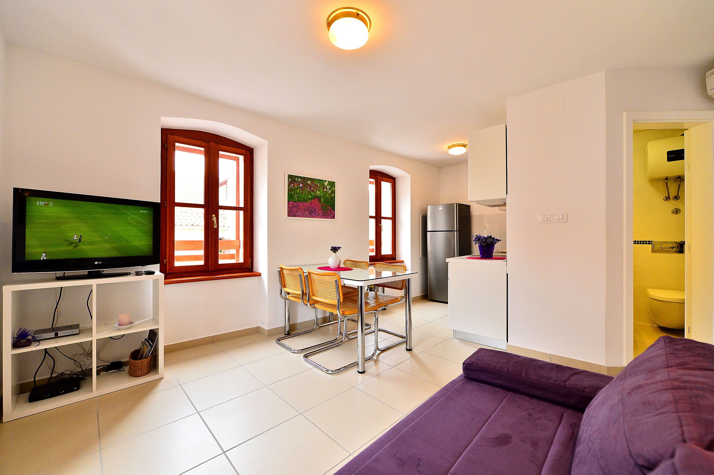 A compact living space with a dining area, a television, and a kitchenette.