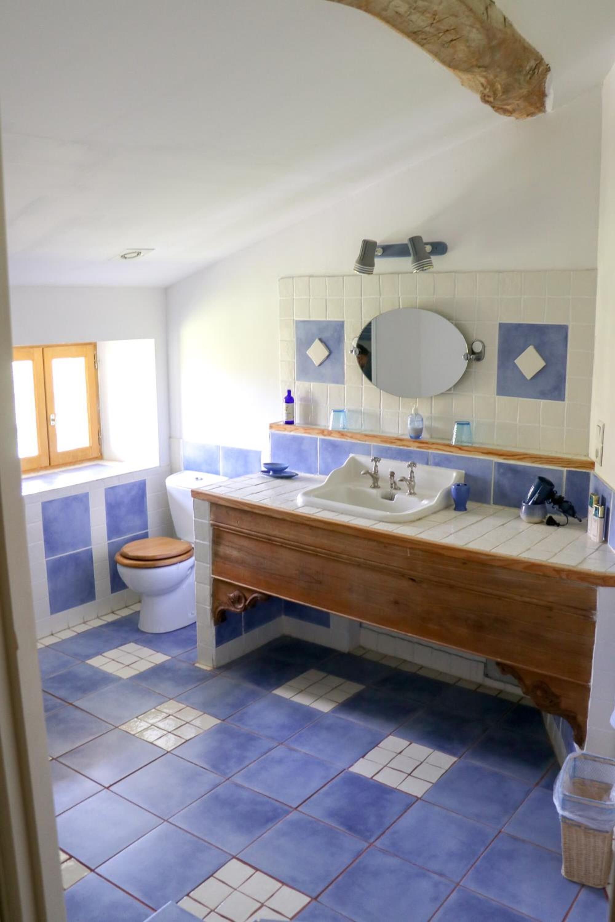 A bathroom with a wooden vanity, white sink, and blue-tiled floor.