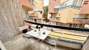 Un balcón con una mesa, sillas y un florero con flores.