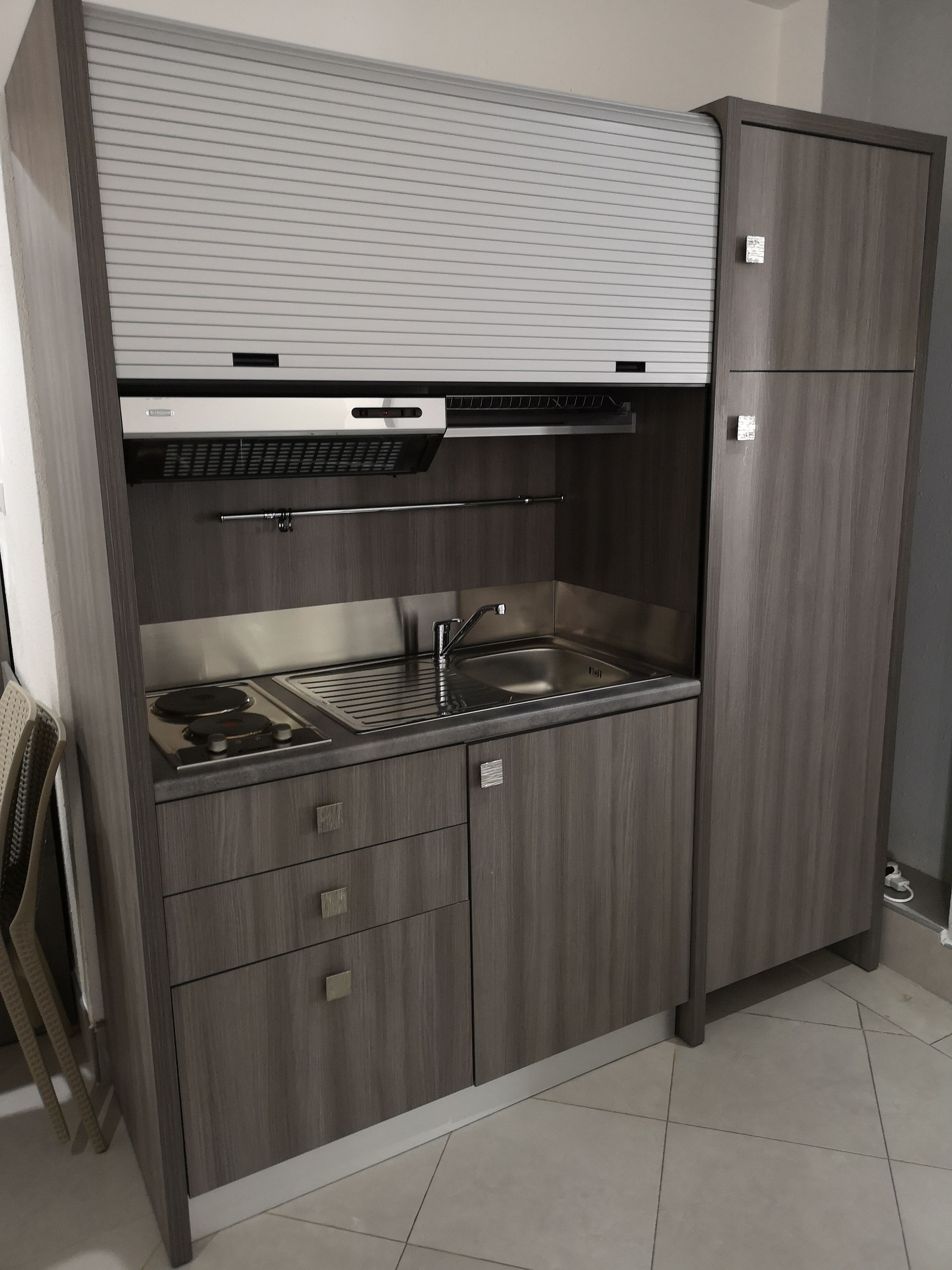A compact kitchen with a built-in stove, sink, and storage cabinets.
