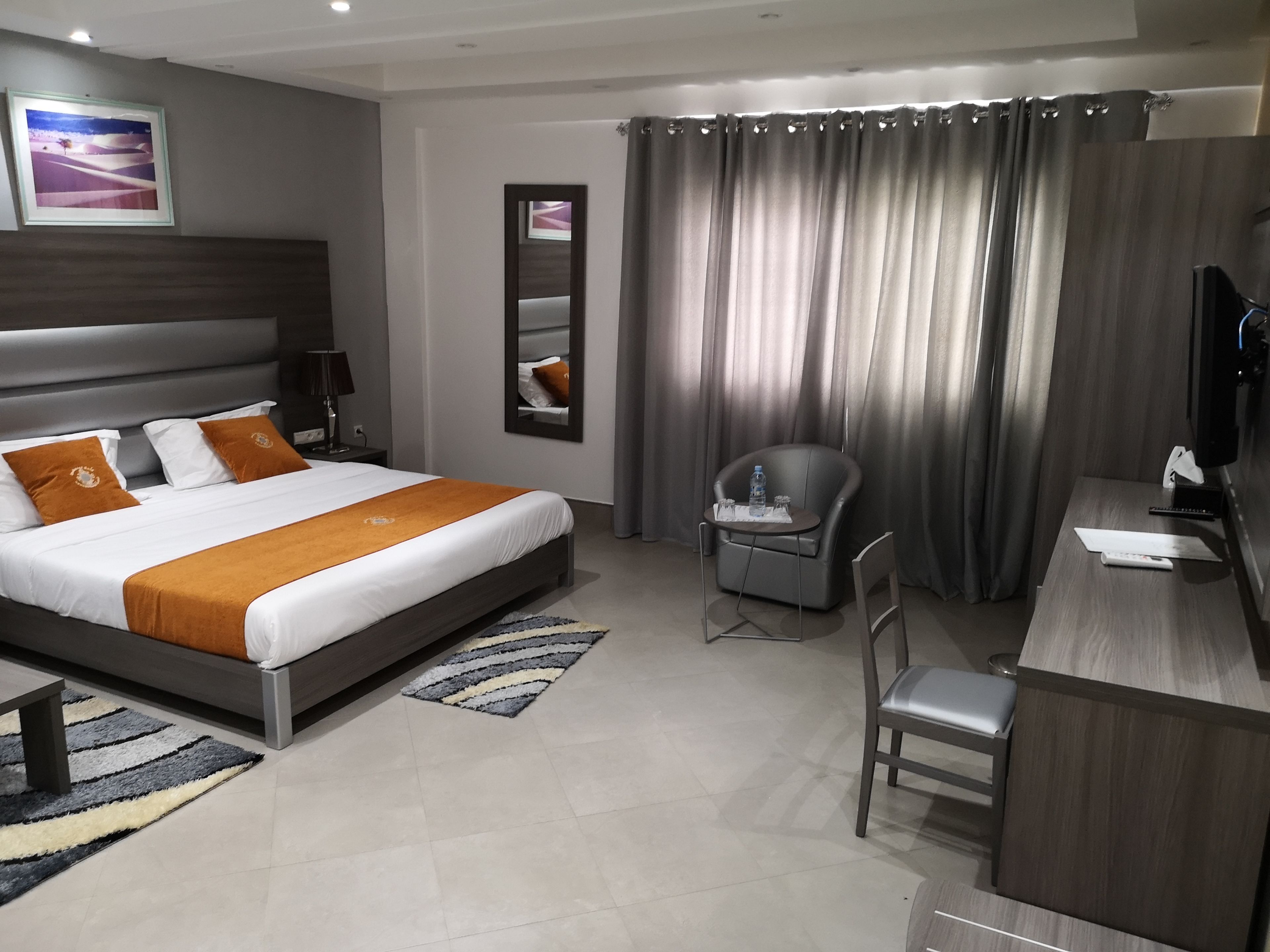 Una habitación de hotel moderna con una cama grande, un escritorio, una silla y un televisor.