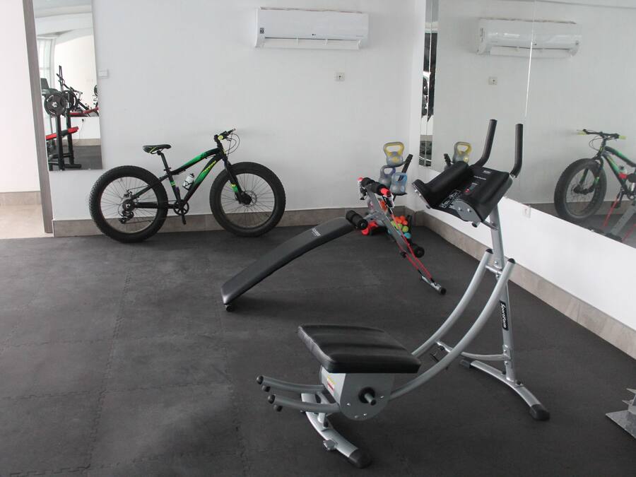 A gym with exercise equipment, a stationary bike, and a mirror reflecting the room.