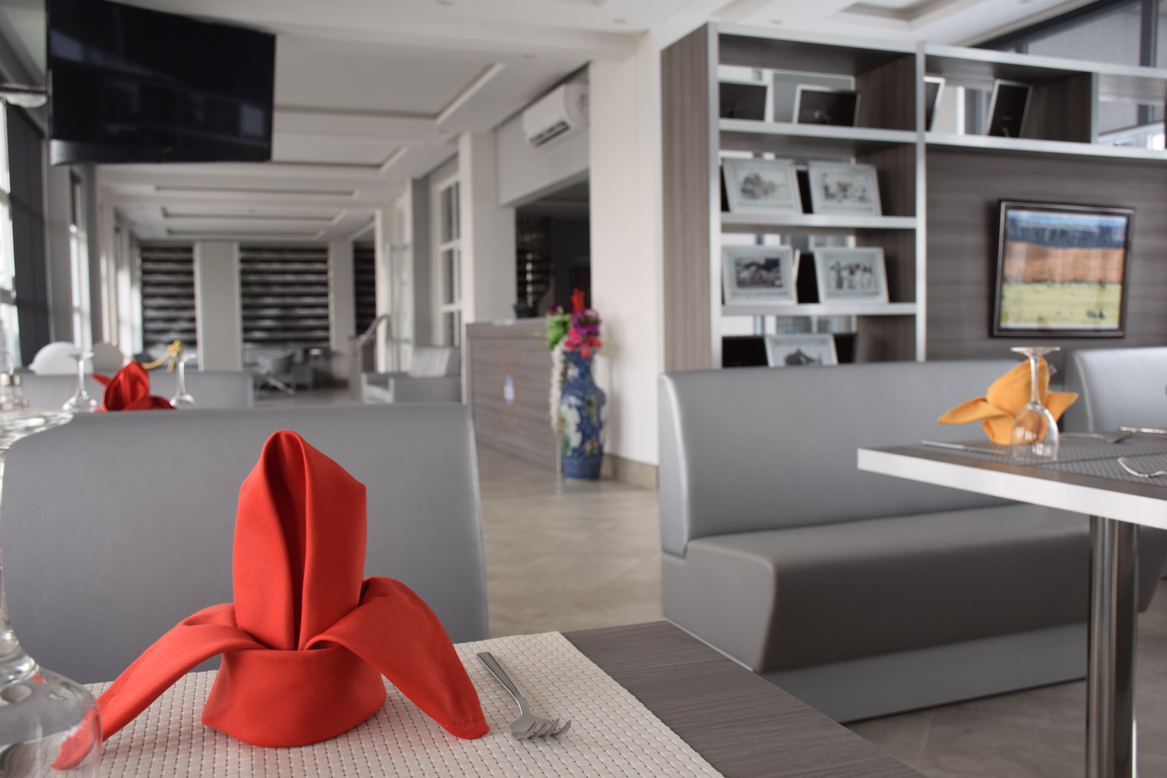 Eine moderne Hotelhalle mit Sitzgelegenheiten, einer Rezeption und einer Wand mit gerahmten Bildern.