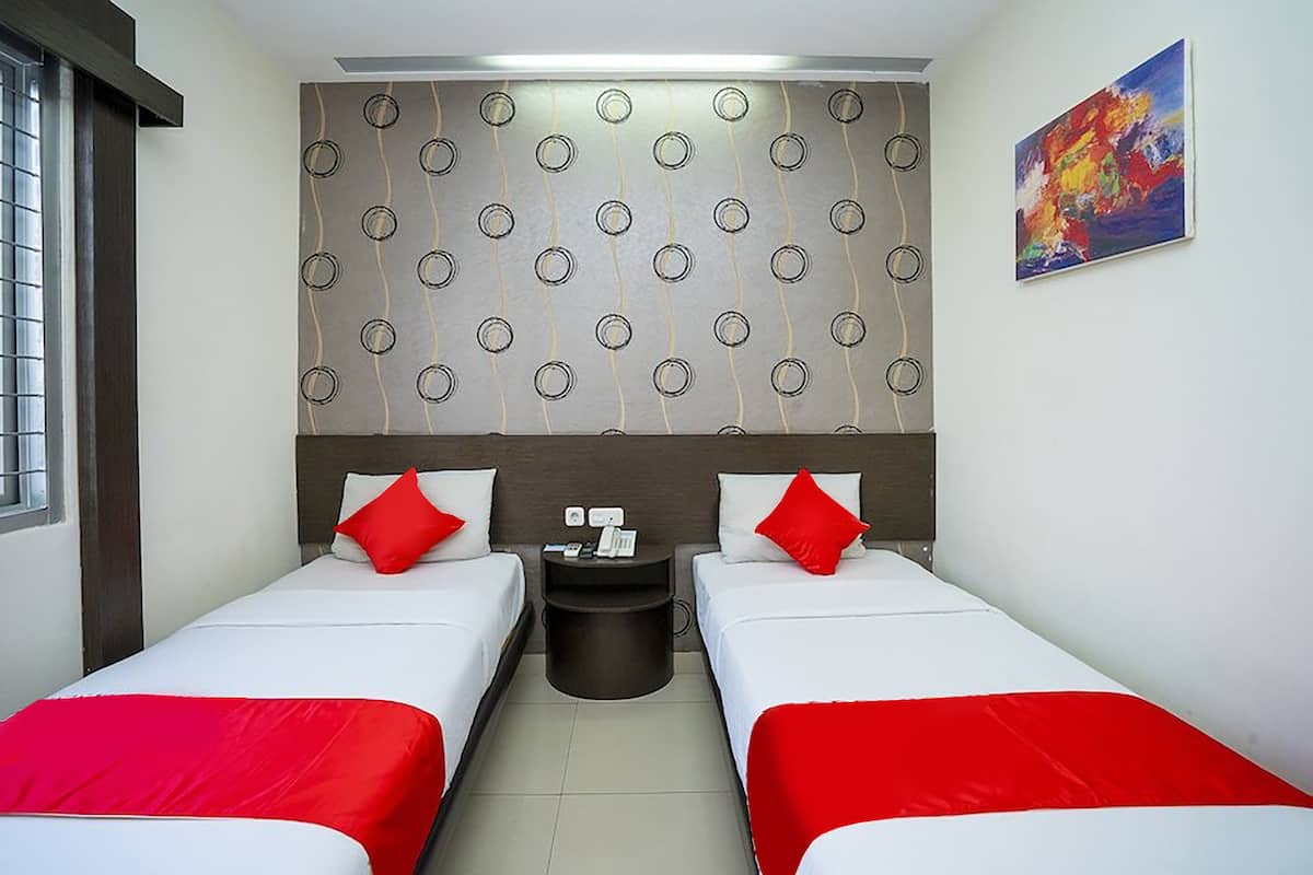 A hotel room with two beds, a nightstand, a wall-mounted artwork, and a window with blinds.