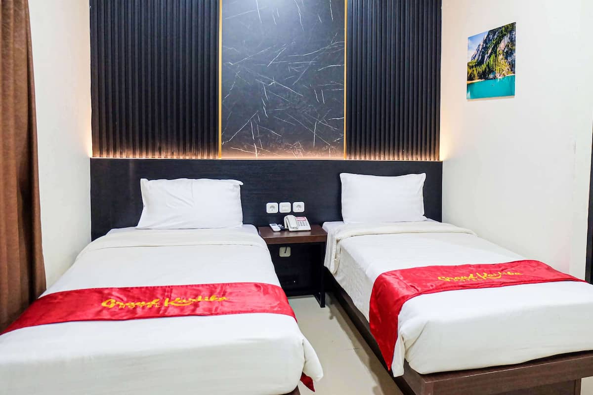A hotel room with two beds, a nightstand with a phone, and a picture on the wall.