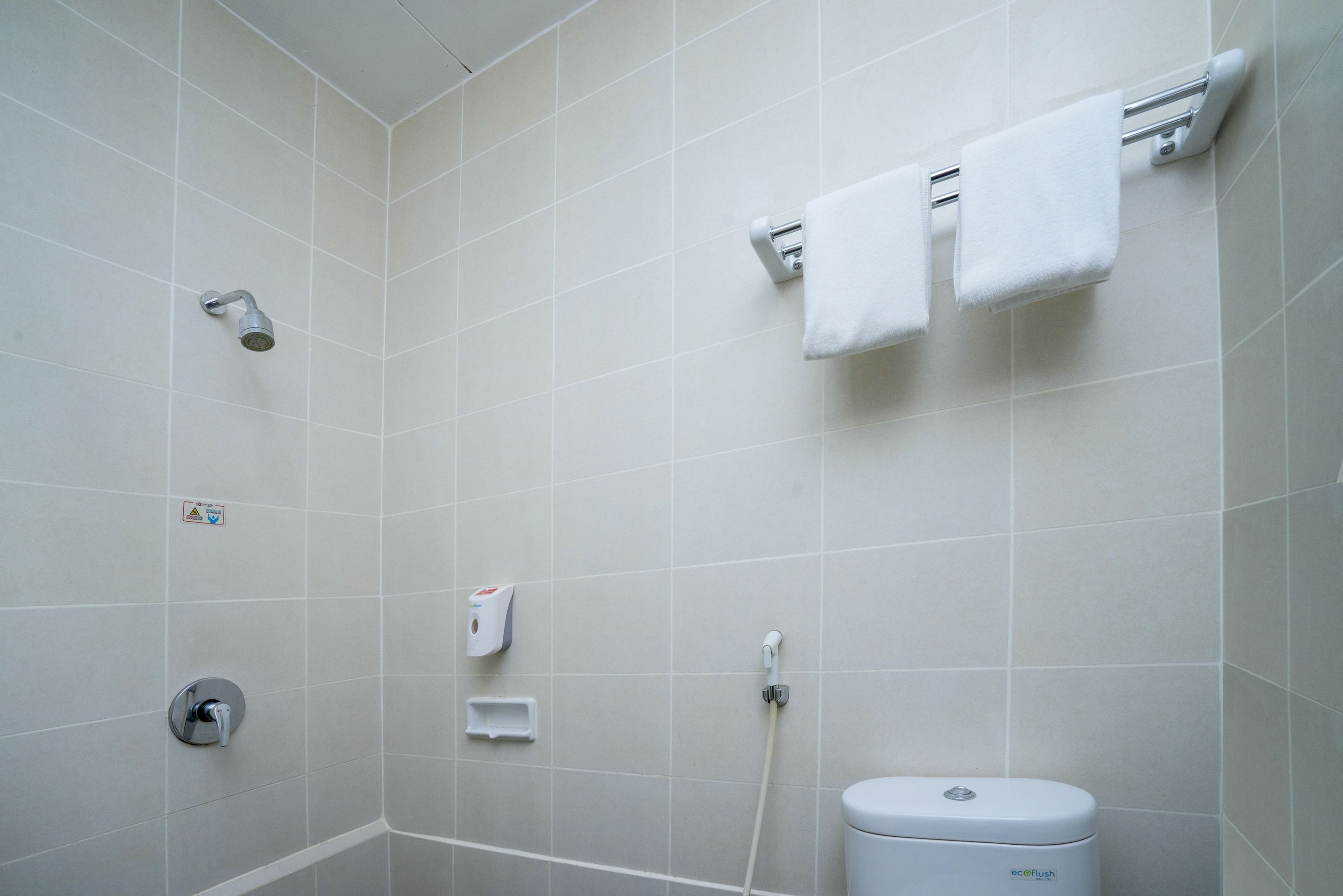 A modern bathroom with a shower, toilet, and towel rack.