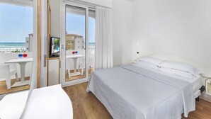 Ett hotellrum med en säng, ett skrivbord och utsikt över stranden.