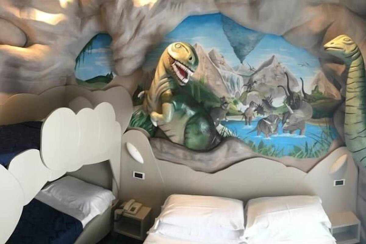Quarto de criança com um mural de dinossauros na parede.
