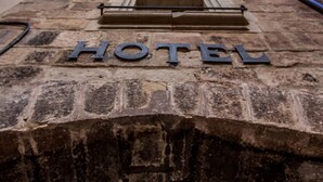 A stone pathway leading to a wooden door with the word "HOTEL" engraved on it. - Hotel Jaime I (Mora de Rubielos)