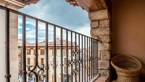 A balcony with a wrought iron railing, a wicker basket, and a view of a street with buildings. - Hotel Jaime I (Mora de Rubielos)