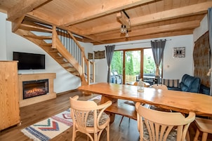 Un comedor de madera con chimenea, una escalera y un televisor en la pared.