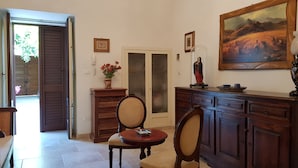 A room with a wooden cabinet, a table with chairs, a door with frosted glass panels, and a painting on the wall. - B&B Le Due Corti (Martignano)