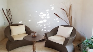 Two wicker chairs with cushions, a small round table, and a decorative vase. - B&B Le Due Corti (Martignano)