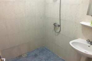 A small bathroom with a shower, a sink, and a mirror.