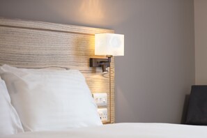 A hotel room with a wooden headboard, a bedside lamp, and a white bed. - Paisley Pear, Brackley by Marston's Inns (Brackley)