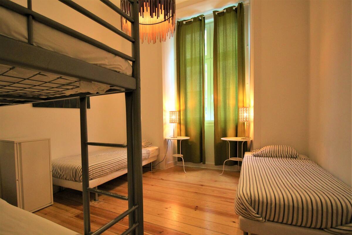 Une chambre de dortoir avec des lits superposés, un bureau, deux chaises et une petite table.