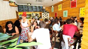A restaurant interior with wooden walls, hanging lights, and a menu board.