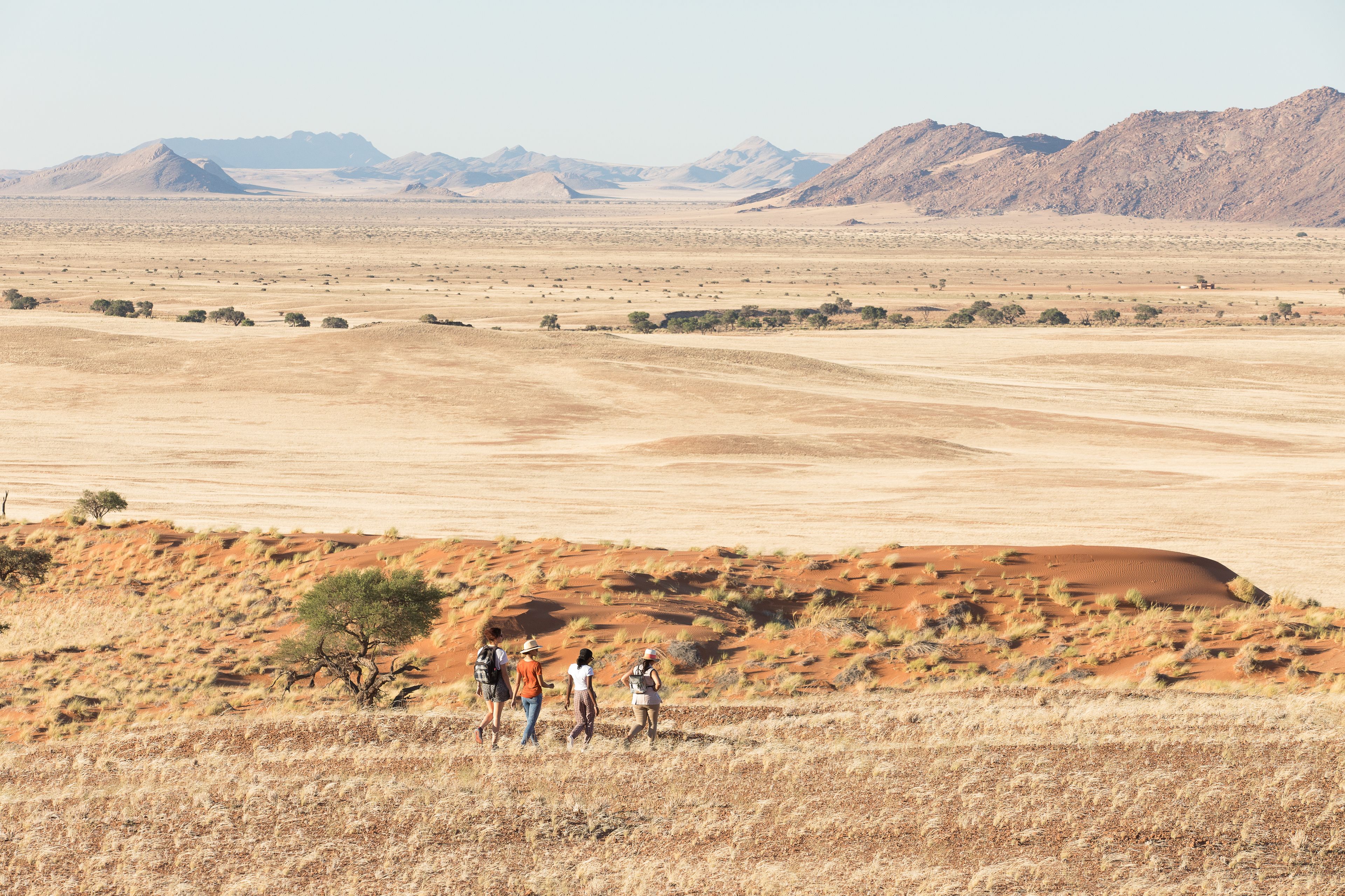 Paisagem desértica com um grupo de pessoas caminhando.