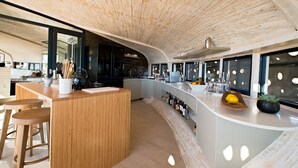 Et moderne køkken med buet træloft, en bar med barstole og et vinskab.
