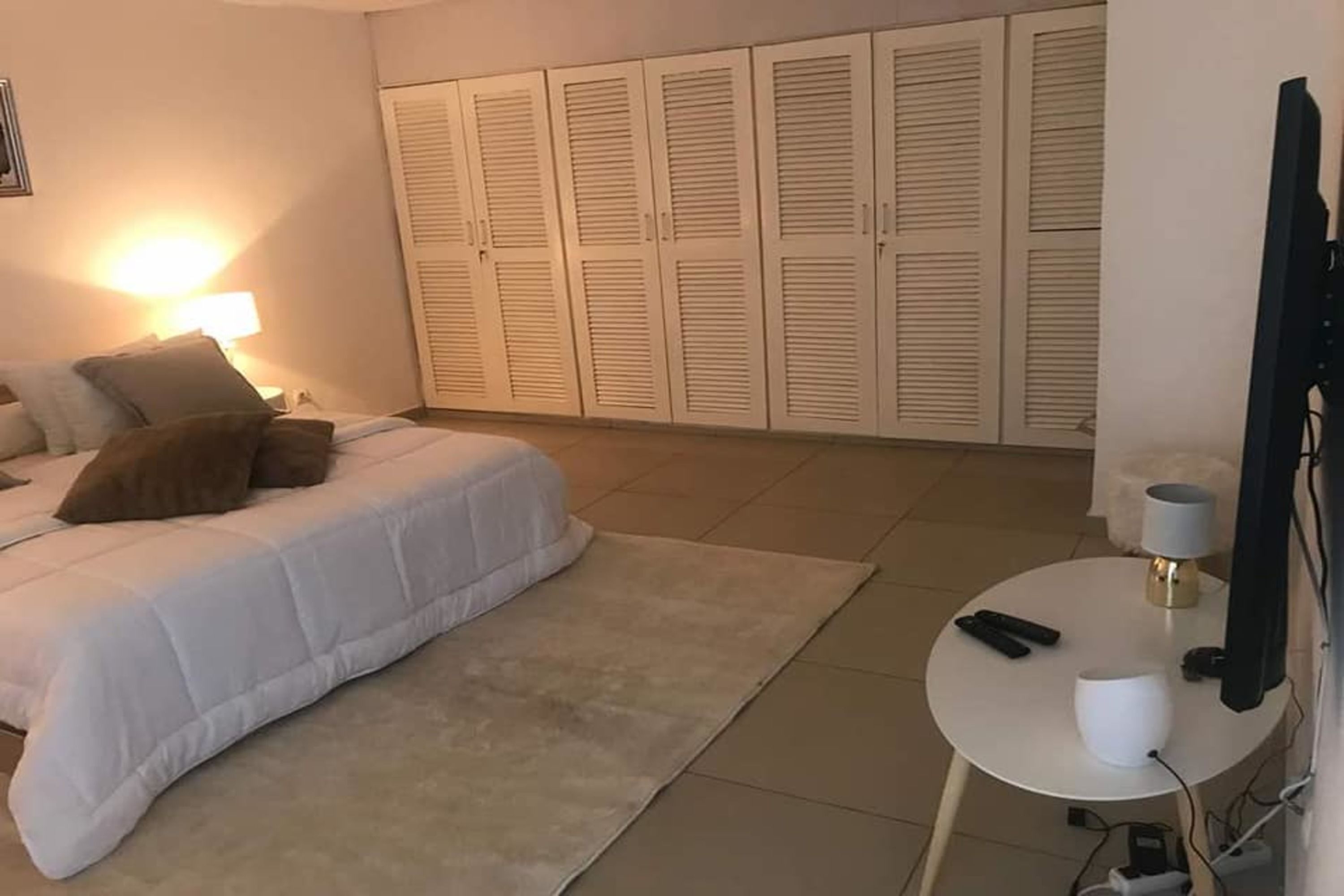 A bedroom with a bed, bedside table, lamp, and a wardrobe.