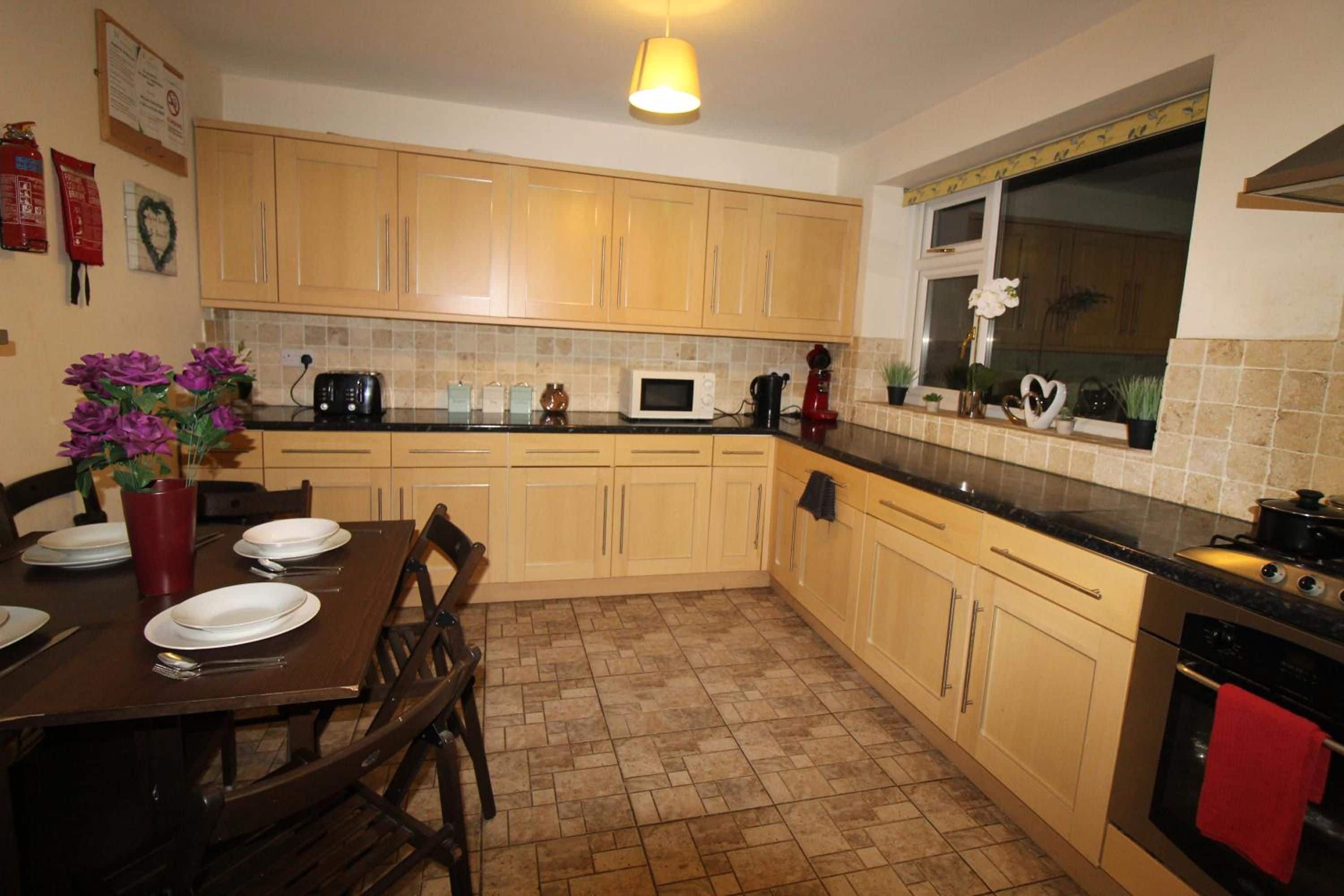 A kitchen with wooden cabinets, a dining table with plates, a microwave, and a stove.