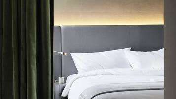 A modern hotel room with a large bed, a bedside table, and a headboard with integrated lighting.
