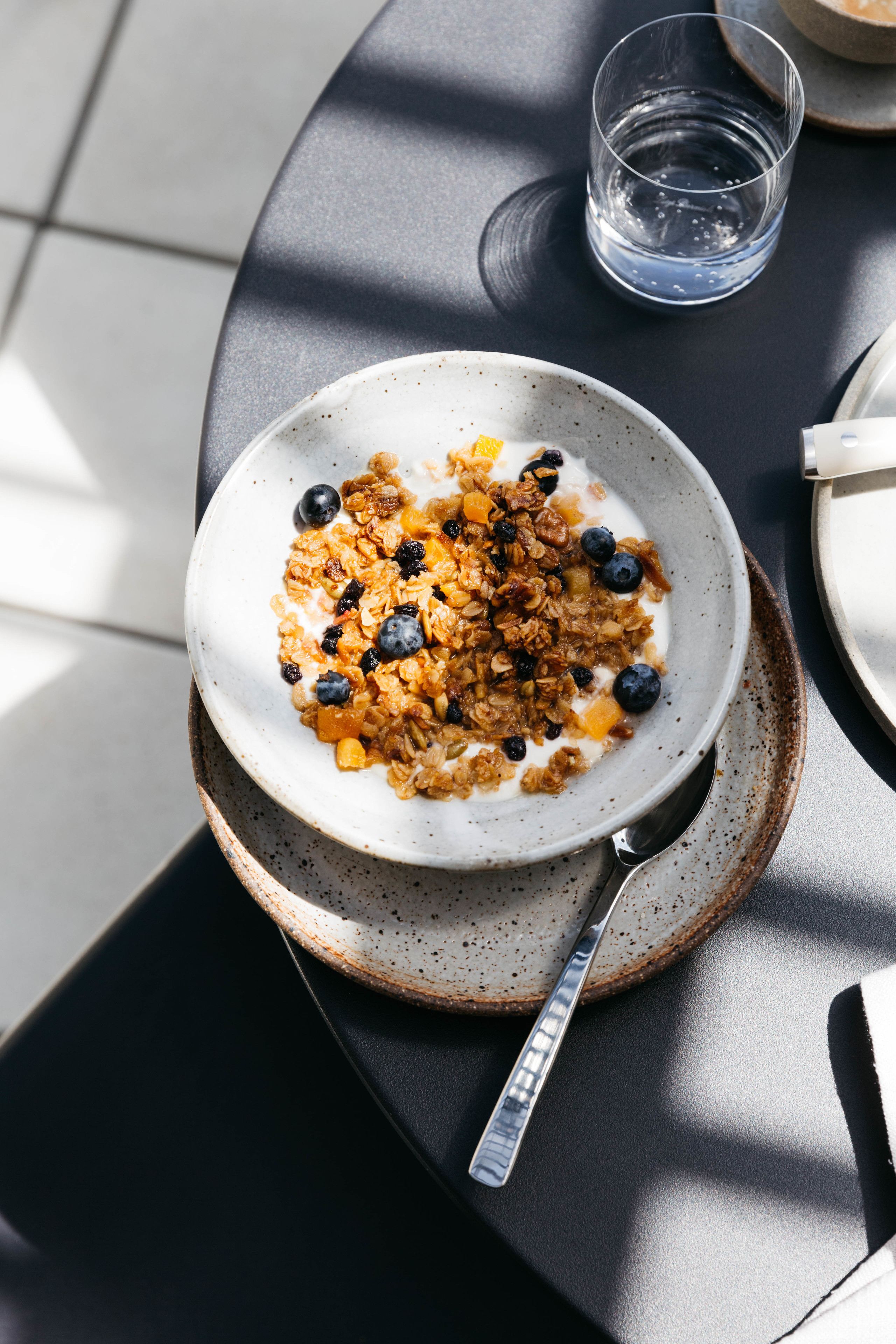 Eine Schüssel Müsli mit Blaubeeren und Granola auf einem Teller.