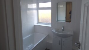 A bathroom with a bathtub, a window, a sink, and a mirror. - Harvey House (Chesterfield)