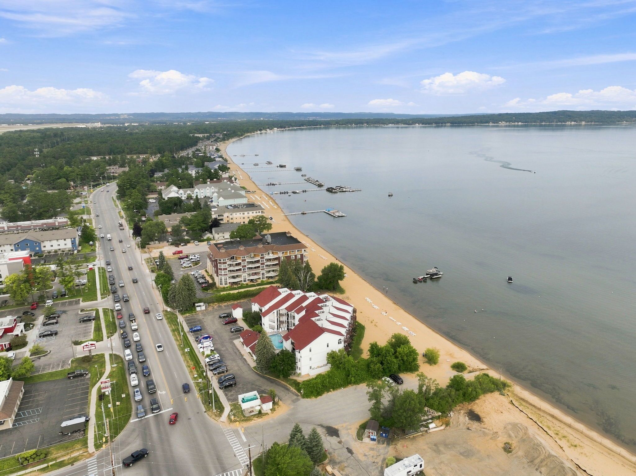 A coastal area with a road, buildings, and a beach.