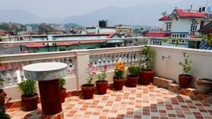 A rooftop terrace with terracotta tiles, potted plants, and a view of the cityscape. - Asian Heritage Inn & Bistro (Burhanilkantha)