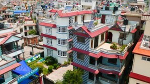 A multi-story building with balconies and a red roof, surrounded by other buildings in a densely populated area. - Asian Heritage Inn & Bistro (Burhanilkantha)