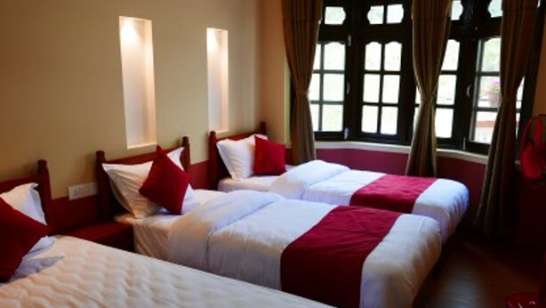 A hotel room with two single beds, a large window with curtains, and a wooden floor. - Asian Heritage Inn & Bistro (Burhanilkantha)