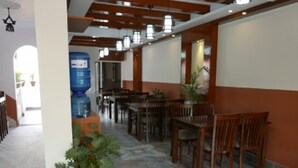 A spacious indoor area with wooden tables and chairs, a water dispenser, and potted plants. - Asian Heritage Inn & Bistro (Burhanilkantha)