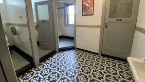 A hotel bathroom with patterned floor tiles, a toilet, a sink, and a shower. - Royal Hotel (Horsham)